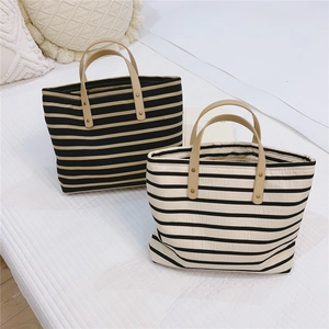 Detail of striped canvas tote bags with leather handles and reinforced metal rivets