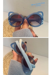 Close-up of blue cat-ear kids sunglasses with glitter frames and gray protective lenses