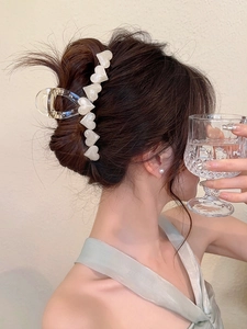 Detail of a large transparent acrylic hair claw clip with pearly white 3D heart motifs
