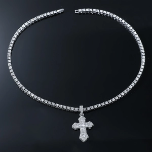 Close-up of sparkling silver cross pendant and iced-out tennis chain on black background