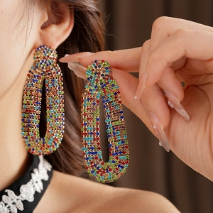 Close-up of vintage oval earrings with colorful zircon stones worn by a model