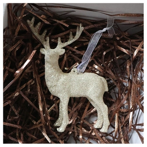 Detail of glittery champagne gold reindeer ornament resting in a festive gift box