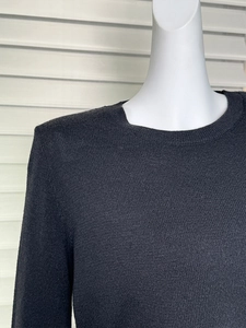 Close-up of the black knit sweater texture and round neckline on a model