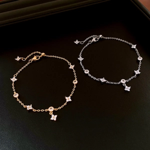 Close-up of gold and silver four-leaf clover zircon bracelets on black leather