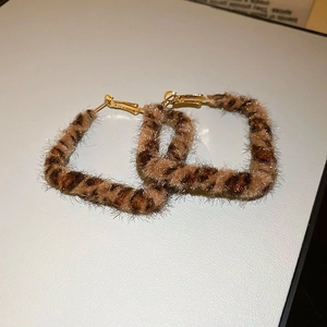 Vue rapprochée de boucles d'oreilles carrées léopard en fausse fourrure et crochets dorés