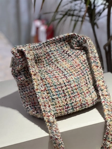 Detailed view of colorful tweed woven shoulder bag texture with side decorative label