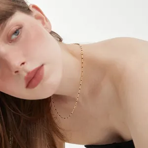 Elegant 18K gold chain necklace with black enamel beads on a female model