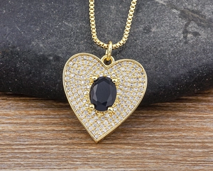 Detail of heart pendant with black oval gemstone and clear zirconias on gold chain