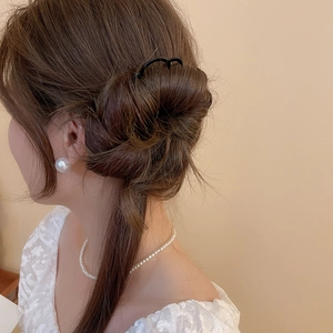 Détail macro d'une épingle à cheveux noire en U pour fixer un chignon élégant et chic