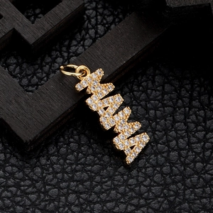 Close-up of gold-plated MAMA pendant with sparkling zircon inlays on textured wood