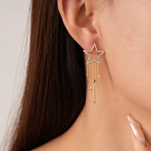 Close-up of model wearing gold star tassel earrings with zircon rhinestone embellishments
