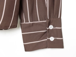 Detail of striped shirt cuff featuring white resin buttons and twill fabric texture