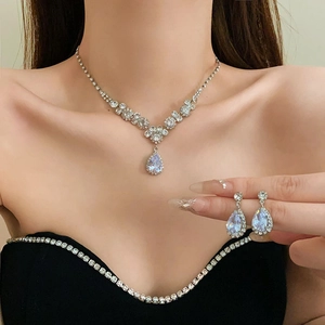 Detailed view of silver flower necklace and teardrop crystal earrings worn by model