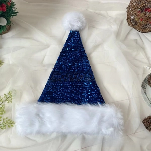 Detail view of dark blue sequined Christmas hat with white plush trim and fuzzy pom-pom