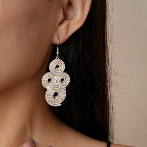 Close-up of artistic spiral woven silver earrings on model with metallic texture details
