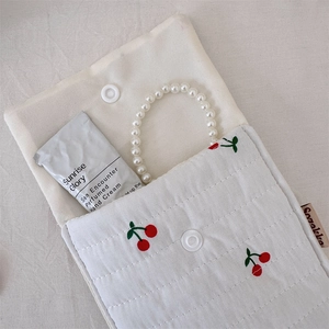 Detailed view of quilted cotton makeup bag with cherry embroidery and button closure