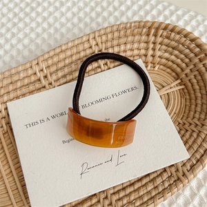 Close-up of amber resin hair tie on a decorative tray with a white romance card