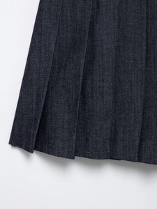 Detail of dark blue denim pleated skirt showing fabric texture and neat pleats
