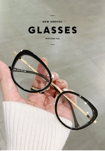 Detail of black and gold cat-eye glasses showing anti-blue light lens and metal frame