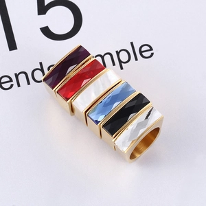 Macro detail of six gold-plated square rings with colorful geometric glass gemstones