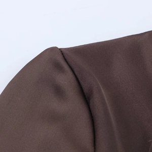 Close-up of deep brown satin fabric showing delicate texture and fine stitching detail
