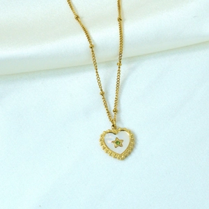 Detail of 14K gold plated heart shell necklace with green stone on white silk