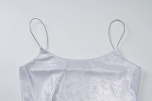 Dettaglio del top glitterato argento con spalline sottili e tessuto strutturato lucido