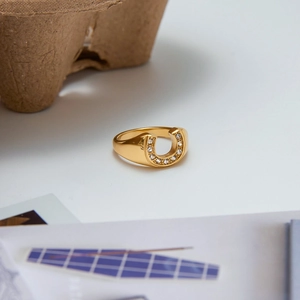 Macro detail of U-shaped gold ring with sparkling cubic zirconia on cardboard background
