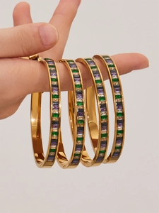 Detail of four gold stainless steel bracelets with emerald and lavender square zircons