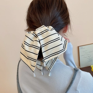Détail d'une pince à cheveux à rayures avec perle, portée par un mannequin élégant