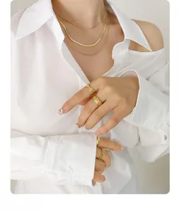 Close-up of gold three-layered necklace and textured rings worn by a model