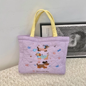 Close-up of lavender quilted handbag with cute dog embroidery and yellow handles