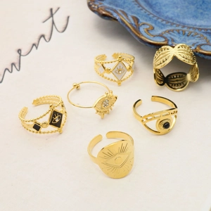 Set of six gold evil eye rings with blue enamel and crystal details on a ceramic dish