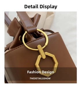 Close-up of brown leather bucket bag showing drawstring closure and gold metal hardware