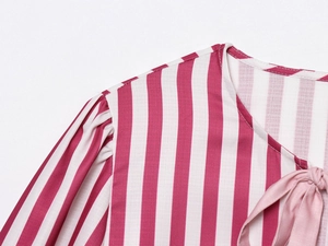 Detail of red and white striped fabric with pink satin ribbon bow and delicate stitching