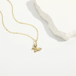 Elegant gold butterfly pendant necklace with fine chain displayed on white stone base