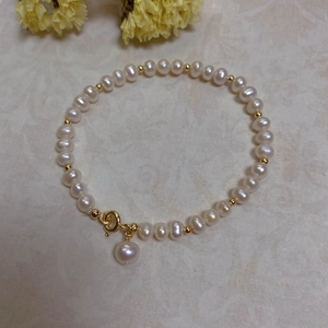 Detail of baroque pearl bracelet with gold beads and spring clasp on marble surface