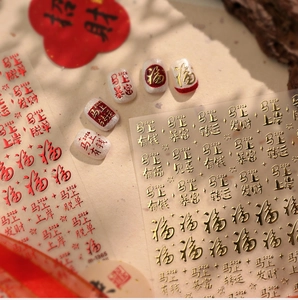Macro detail of Chinese New Year nail art stickers with golden calligraphy and red symbols