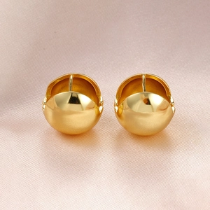 Detailed close-up of golden sphere stud earrings with a high-polished mirror finish