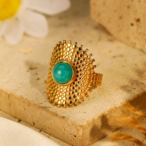 Macro view of gold plated stainless steel ring with green turquoise stone on a stone base