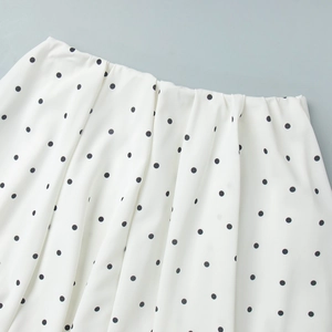 Close-up of white polka dot fabric texture and neat stitching on high-quality woven dress