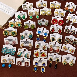 Collection of vintage-style gold earrings with colorful gems and pearls on display cards