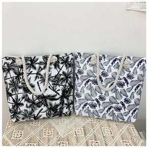 Detail view of printed canvas tote bags with thick rope handles and tropical leaf patterns