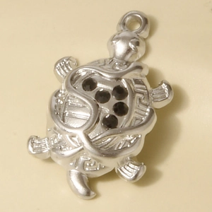 Macro shot of silver turtle pendant in stainless steel with black stone inlay details
