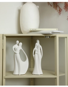 Close-up of minimalist matte white ceramic abstract couple figurines with sandy texture