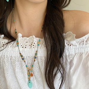 Close-up of bohemian turquoise beaded necklace on model in white lace top