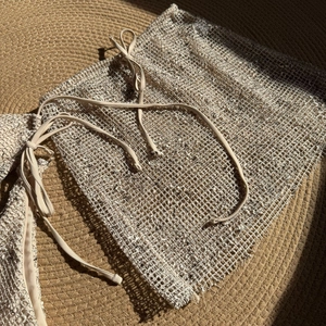 Detail of beige crochet mesh swimsuit cover-up with drawstring on woven straw mat