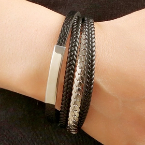 Detailed view of multilayer braided black leather bracelet with silver steel bar on wrist