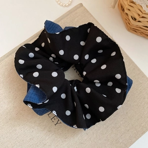 Close-up of double-layered polka dot and denim fabric scrunchie on a decorative book
