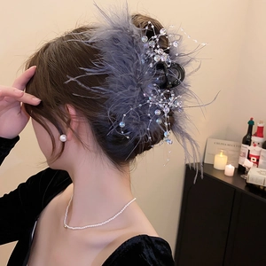 Detail view of large grey feather hair claw clip with beads styled on model's hair